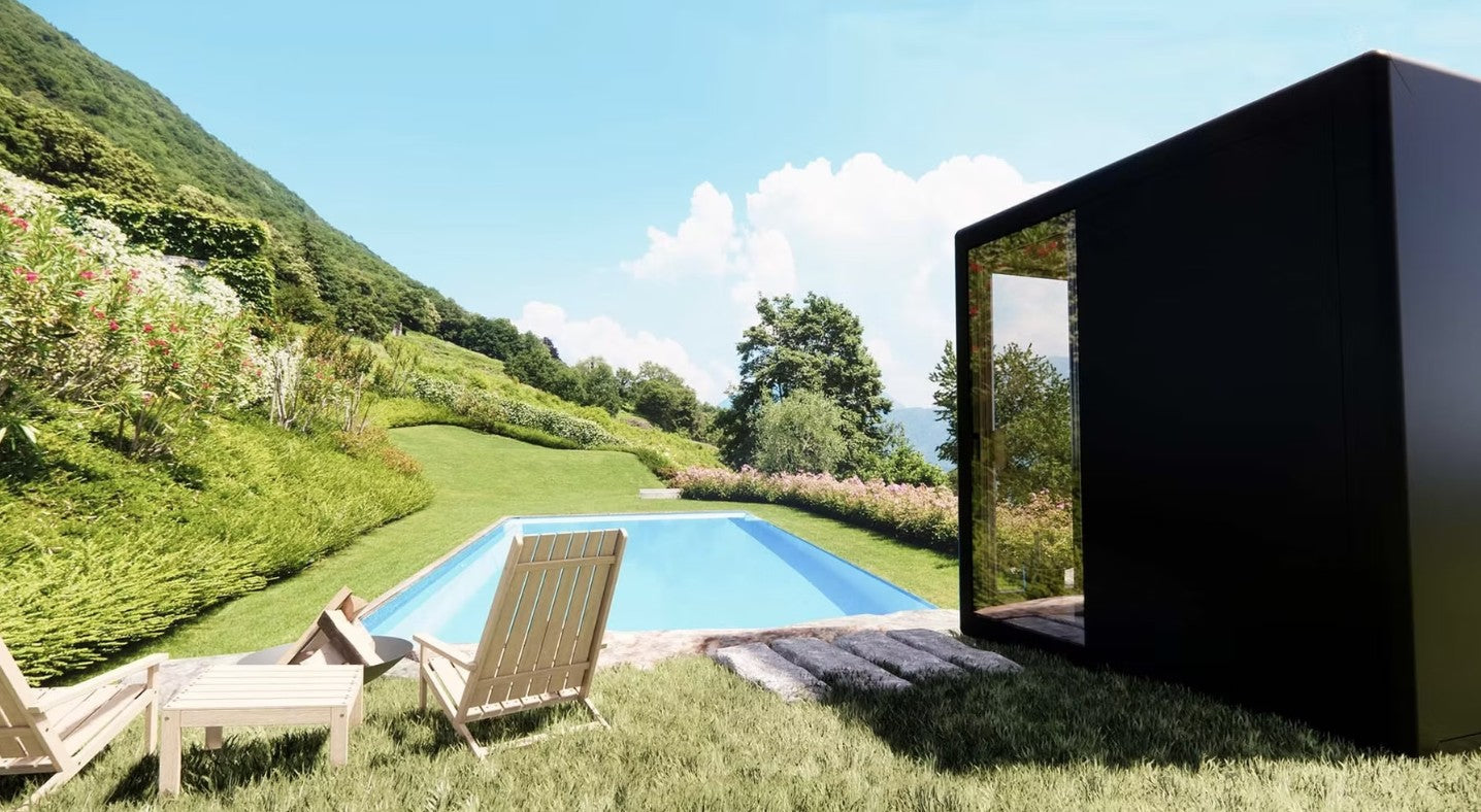 Koya Modern black Cube Outdoor Traditional Sauna in a scenic outdoor setting with a pool and greenery.